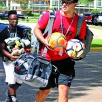 Students armed with soccer balls and other equipment head to their dorms on campus.