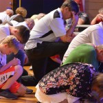 Attendees of the Tomorrow's Hope Crusade kneel down in prayer for those who do not know Christ.