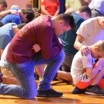 Attendees of the Tomorrow's Hope Crusade kneel down in prayer for those who do not know Christ.
