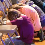 Attendees of the Tomorrow's Hope Crusade kneel down in prayer for those who do not know Christ.