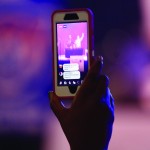 A smartphone camera captures a member of the praise team.