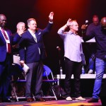 An entourage of evangelists, musicians and pastors participate in a time of worship.