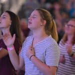 A woman raises her hands in praise during a Rush of Fools mini-concert. Brian Blackwell photo