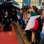 Volunteers greet a special guest as he makes his way down the red carpet at Night to Shine in Gonzales..