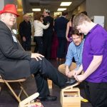 Volunteers shine shoes of a special guest enjoys a Night to Shine at the Lamar Dixon Expo Center in Gonzales.