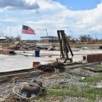 The American flag flies in the distance amid a pile of rubble near Cameron. Norm Miller photo/Taken Sept. 12.