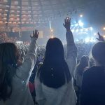 Students raise their hands in praise during a session of YEC.