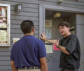 Taylor Field, right, pastor of the Graffiti Church, shares information about prayer requests with a member of the community. Photo by Jim Veneman